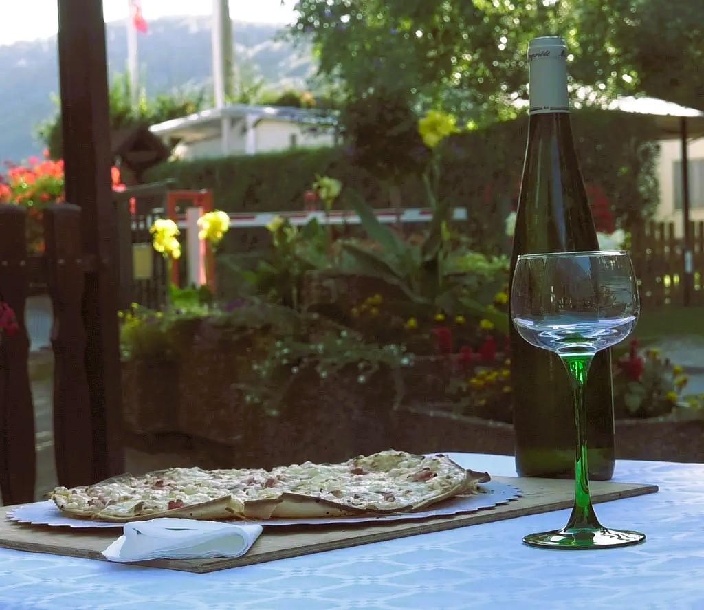 Tarte flambée servie au camping avec du vin blanc de l'Alsace